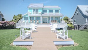 A two-story house with a deck and outdoor seating. - Serenity by the Sea: Nostalgic Oceanfront Home with Room for the Whole Family (Oak Island)