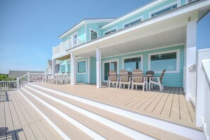 Eine mehrstufige Holzterrasse mit Sitzgelegenheiten, Geländern und blauem Himmel.