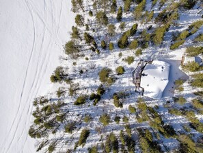 Une vue aérienne d’un paysage enneigé, parsemé d’arbres, sous un ciel dégagé.