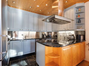 Une cuisine moderne avec des meubles de couleur bleu clair, des appareils en acier inoxydable et un plafond en bois.