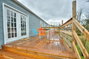 A wooden deck with a railing, a blue chair, and a wooden table.