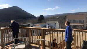 A deck with a view of a mountainous landscape, a flag, and a house with a star decoration.