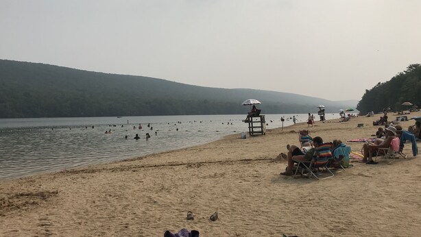 A beach with people swimming and relaxing on the sand.