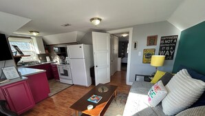A compact living space with a kitchenette, a sofa with cushions, a coffee table, and a rug.