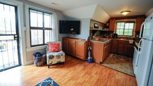 A compact kitchen with wooden cabinets, a built-in microwave, and a refrigerator.