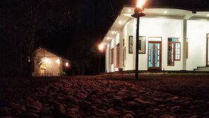 A building with a brick facade and a white exterior, featuring a large wooden door and multiple windows. - The Grand Leisure Villa (Udawalawa)