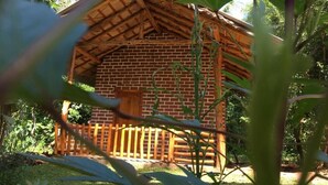 A rustic wooden cabin with a thatched roof, surrounded by lush greenery. - The Grand Leisure Villa (Udawalawa)