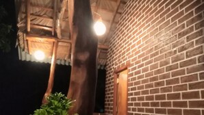 A brick building with a wooden door and a window, surrounded by greenery. - The Grand Leisure Villa (Udawalawa)