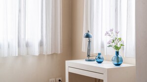 A white bedside table with a blue lamp and a vase with flowers. - Santa Fosca Design Apartment R&R (Venecia)