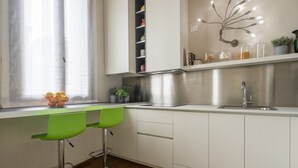 A modern kitchen with white cabinets, a stainless steel sink, and a green chair. - Santa Fosca Design Apartment R&R (Venecia)