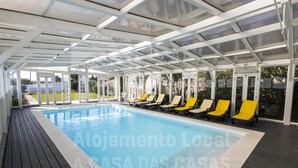 An indoor swimming pool with a covered area, lounge chairs, and a view of the outdoors. - Villa S. Lourenço by ACasaDasCasas (Ericeira)