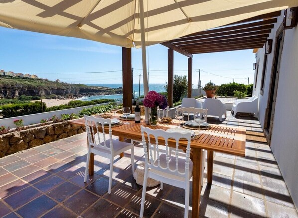 Enjoy al fresco dining on this terrace overlooking the sea and a scenic cliff.