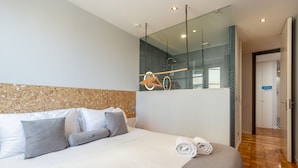 Et moderne hotelværelse med en stor seng, et træhovedgærde, et spejl og trægulv.