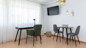A modern dining area with a wooden table, two chairs, a TV mounted on the wall, and a hanging light fixture.