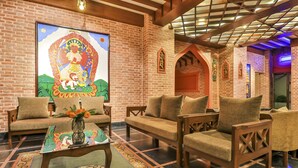 A room with brick walls, wooden furniture, and a large mural. - Hotel Bhadgaon (Bhaktapur)