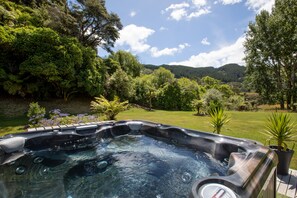 Un jacuzzi rodeado de abundante vegetación y un paisaje montañoso.