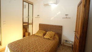 Une chambre à coucher comprenant un lit, une armoire, un miroir et un appareil de climatisation.