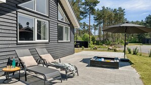 A patio with two lounge chairs and a table, a fire pit, and a large umbrella. - Pet friendly home in Nexø with kitchen (Nexø)