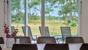 A dining area with a view of a grassy field and trees through large windows. - Pet friendly home in Nexø with kitchen (Nexø)