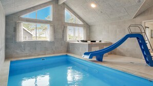 An indoor swimming pool with a blue slide, large windows, and a kitchen area. - Pet friendly home in Nexø with kitchen (Nexø)