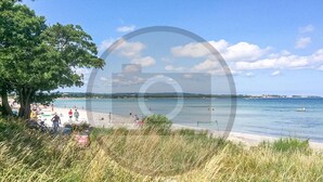 A beach with people, a boat, and a clear sky. - Pet friendly home in Nexø with kitchen (Nexø)