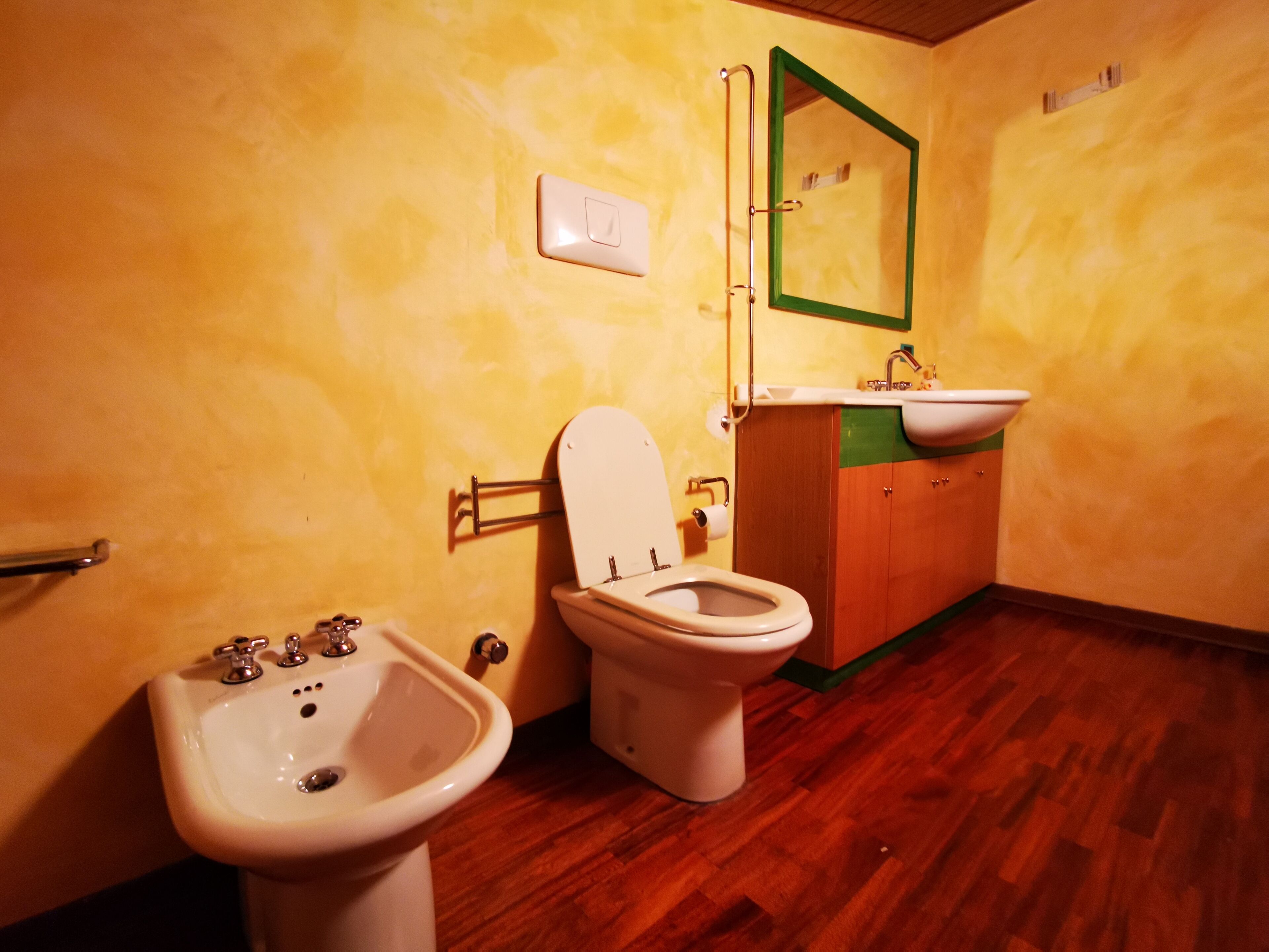 Een kleine badkamer met toilet, hygiëneschuimer en wastafel.