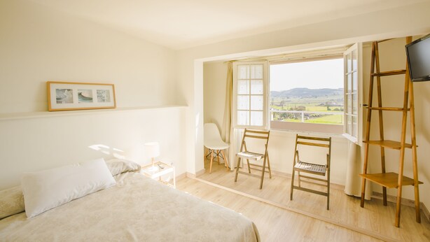 Un dormitorio con cama, escritorio, silla, televisión y ventana con vista.