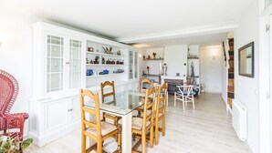 Un comedor con una mesa de vidrio y sillas de madera, rodeado de armarios blancos con puertas de cristal.