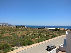 A coastal road with a van, buildings, and a clear view of the sea.