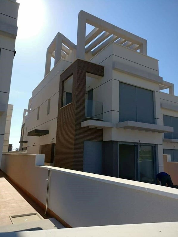 A modern multi-story building with a flat roof, large windows, and a mix of white and brown exterior materials.