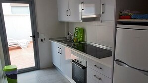 Ett modernt kök med vita skåp, ett kylskåp i rostfritt stål och en inbyggd ugn.