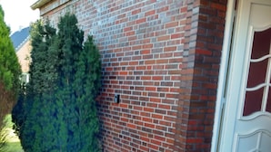 Un bâtiment en briques avec une porte blanche et un petit porche.