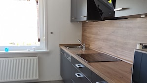 Une cuisine moderne avec des meubles gris, un plan de travail en bois et une fenêtre agrémentée de rideaux.