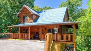 Une cabane rustique en rondins de bois, avec un toit en métal, une véranda en bois et une enseigne indiquant la présence d’un restaurant.