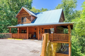 A rustic log cabin with a metal roof, wooden porch, and a sign indicating a restaurant.