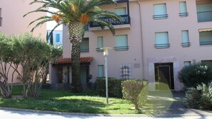 A multi-story building with balconies, a palm tree, and a well-maintained garden. - Cozy studio in Collioure with sunny terrace (Collioure)