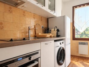 A modern kitchen with a built-in washing machine, a coffee maker, and a window with a view. - Cozy studio in Collioure with sunny terrace (Collioure)
