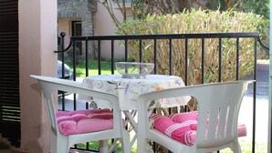 A balcony with a table and two chairs, each with pink cushions. - Cozy studio in Collioure with sunny terrace (Collioure)