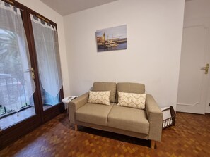 A living room with a sofa, a small table, a picture on the wall, and a door. - Cozy studio in Collioure with sunny terrace (Collioure)