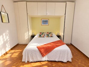 A bedroom with a bed, two bedside tables, a nightstand, a framed picture on the wall, and a hanging mirror. - Cozy studio in Collioure with sunny terrace (Collioure)
