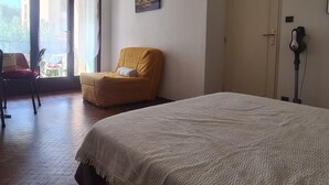 A hotel room with a bed, a chair, a door, and a window with a view of the outside. - Cozy studio in Collioure with sunny terrace (Collioure)