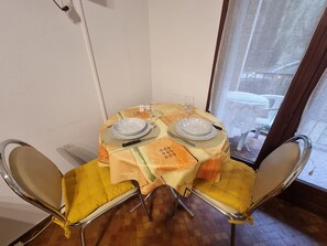 A dining table with two chairs, a patterned tablecloth, and a window view. - Cozy studio in Collioure with sunny terrace (Collioure)