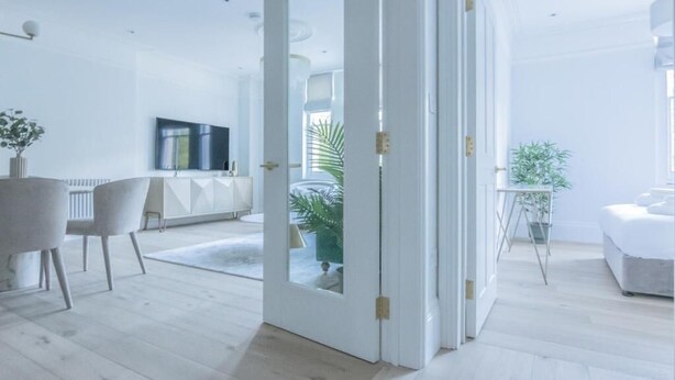A modern, open-plan living space with a dining area, a television, and a potted plant. - Bright 3-room apartment (London)