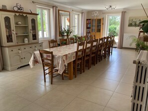 A dining area with a long table, chairs, a cabinet with glass doors, and a radiator. - Beautiful Secluded All Ensuite Property with Private Heated Pool – Sleeps 15 (Fonroque)