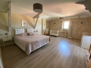 A bedroom with a large bed, a white radiator, a wooden chair, and a stone wall. - Beautiful Secluded All Ensuite Property with Private Heated Pool – Sleeps 15 (Fonroque)
