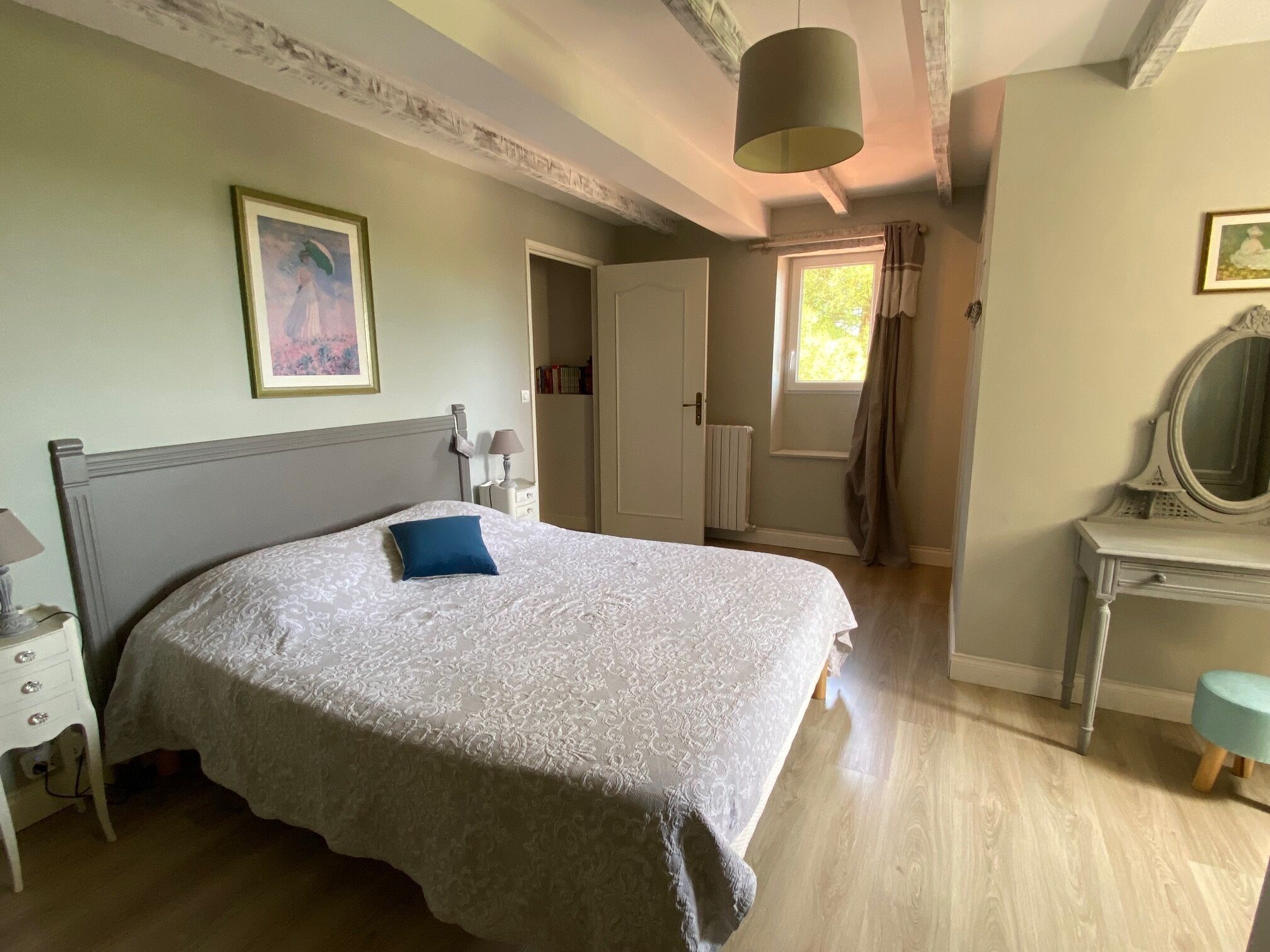 A bedroom with a bed, a dresser, a mirror, a door, and a window.