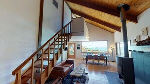 Ein modernes Interieur mit einer Holztreppe, einem Essbereich mit Blick und einem Kaminofen.