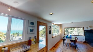 Une cuisine dotée de grandes fenêtres, un coin repas avec une table et des chaises, et une vue sur l’extérieur.