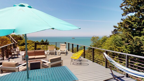Eine Terrasse mit Gartenmöbeln, einer Hängematte und Blick auf den Ozean.