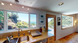 A kitchen with a sink, countertop, and large windows offering a view of the outdoors.